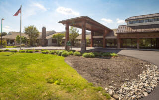 Front entrance of Masonic Village at Warminster, a large building with large windows and a circular driveway in front.